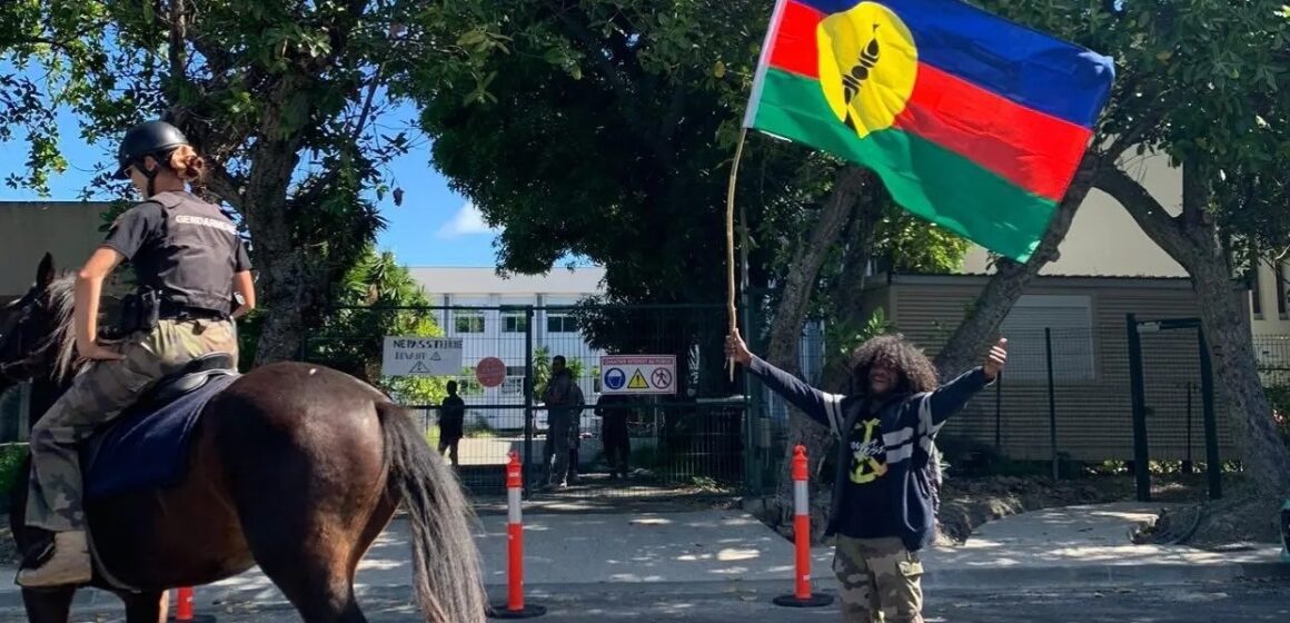 Un habitant agite le drapeau kanak au passage d’un agent de la gendarmerie montée dans le sillage des manifestations contre le dégel du corps électoral. Nouvelle-Calédonie, 11 mai 2024. Photo : DR